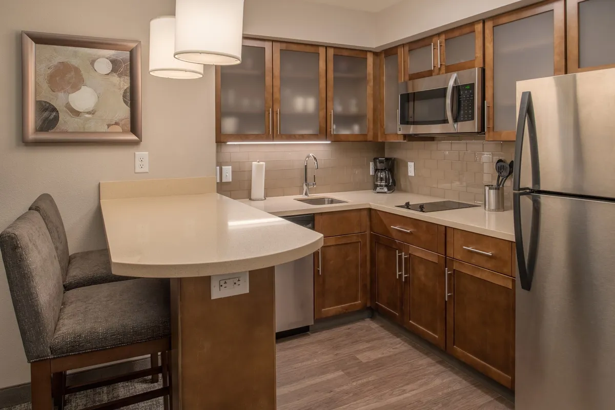 This image showcases a modern kitchen featuring a kitchen island, stainless steel appliances, and tastefully framed artwork. The space is arranged for cooking and socializing, with visible cookware and dishware enhancing the feeling of a fully equipped, functional kitchen.