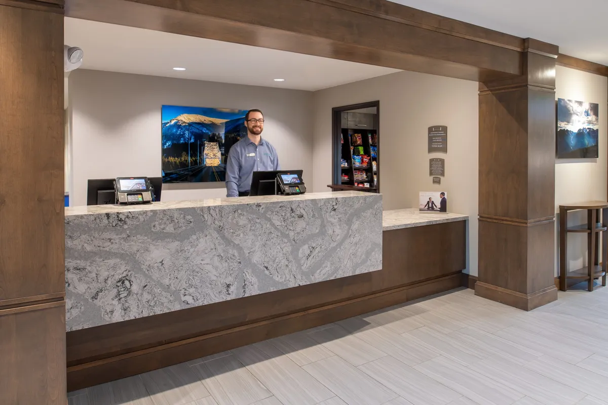 This image captures the property’s reception area, featuring a welcoming reception desk staffed by a friendly team member. The artwork on the wall brings a local touch, and the overall scene exudes an inviting and professional atmosphere—guests are being checked in or assisted with questions about the area.