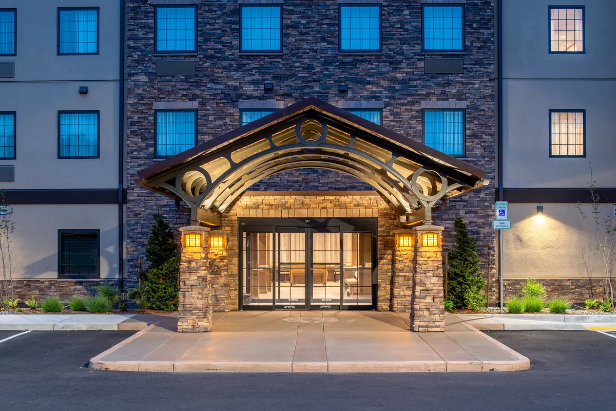 The arched entrance of the property, framed by stone pillars and illuminated lanterns, creating a warm and secure welcome. The area hints at the anticipation of arrival and the beginning of family adventures.