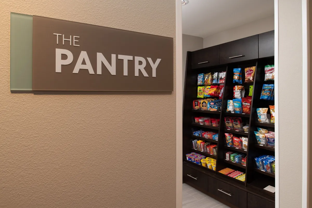 This image showcases the property’s pantry area, where shelves are filled with a variety of snacks. Guests are seen selecting their favorites and sharing light-hearted moments, creating a casual, communal atmosphere ideal for informal networking or unwinding after a busy day.